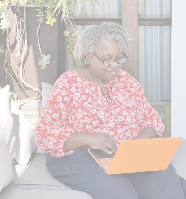 Tania Russell sitting on a couch working on a laptop